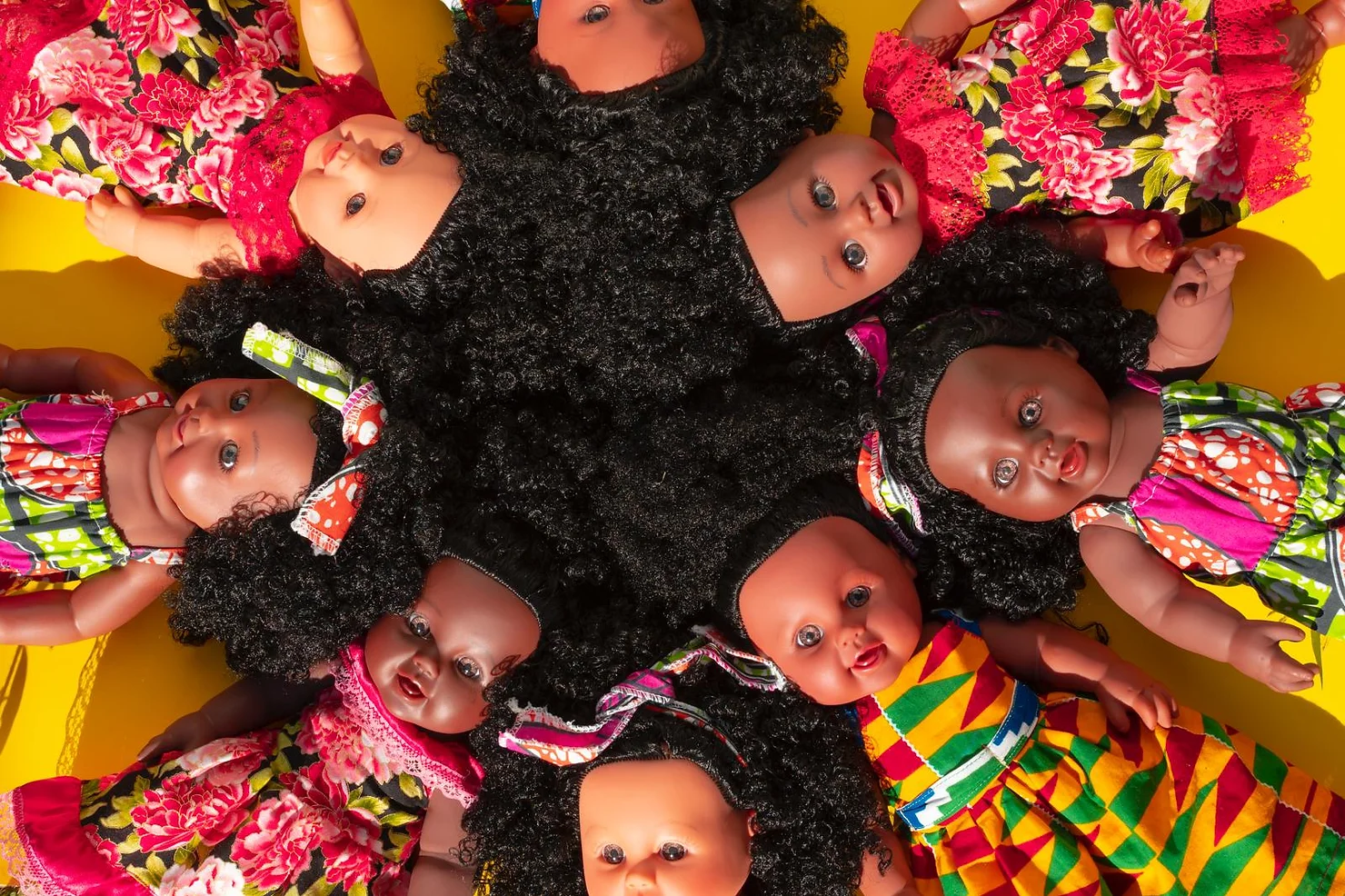 Black dolls laying in a circle with hair connecting