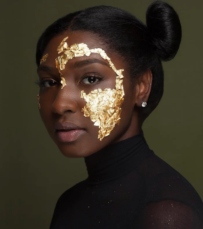 African decent presenting young women with a facial shot of half gold flakes around eyes and cheek