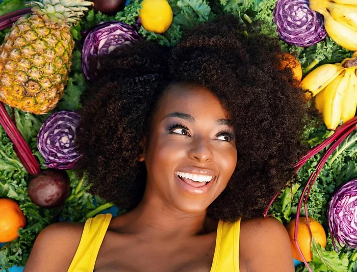 africana pesenting woman with afro in a bed of fruit head shot. 