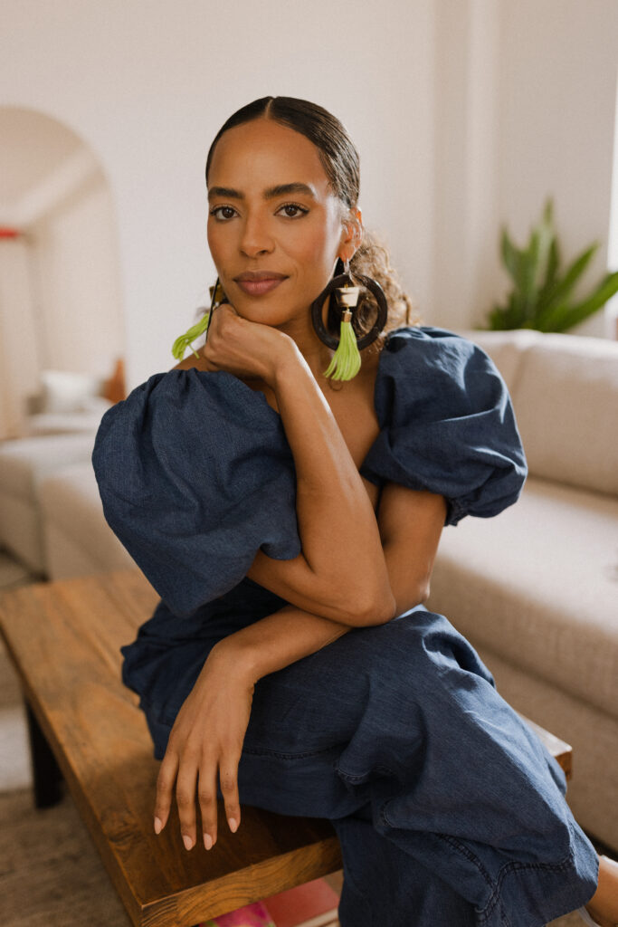 Haitian woman smiling with dark blue denim dress and hands on her chin